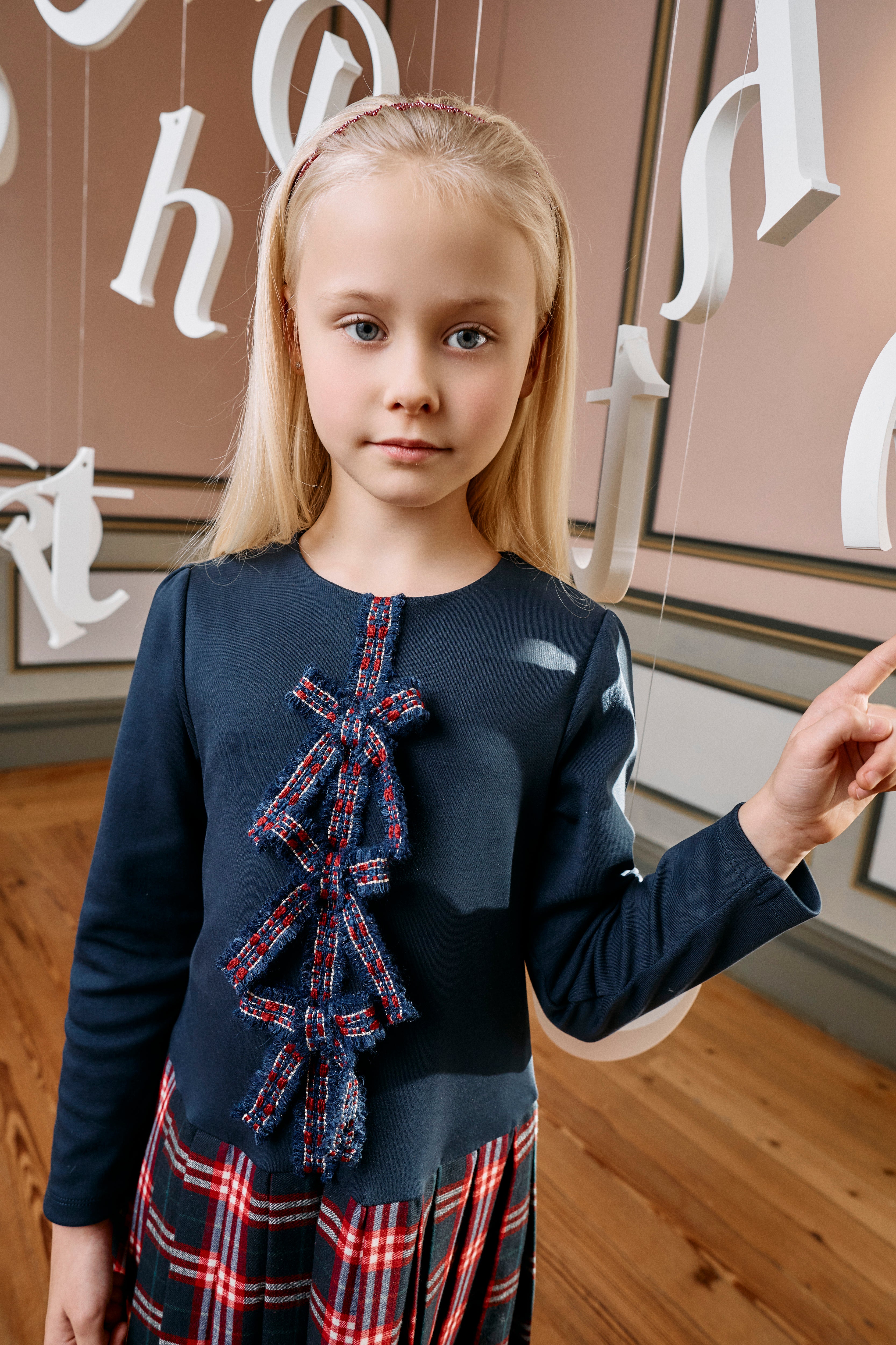 Girl wearing Patachou navy tartan Christmas dress with statement bows