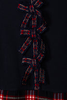 Close-up of Patachou navy Christmas dress with red tartan bow details