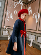 Girl wearing Patachou Marine navy coat with red collar and bow detail