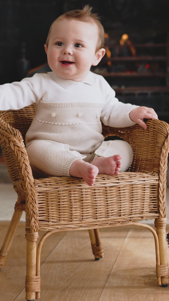 Baby wearing Emile et Rose Kenzie knitted babygrow with pearl buttons