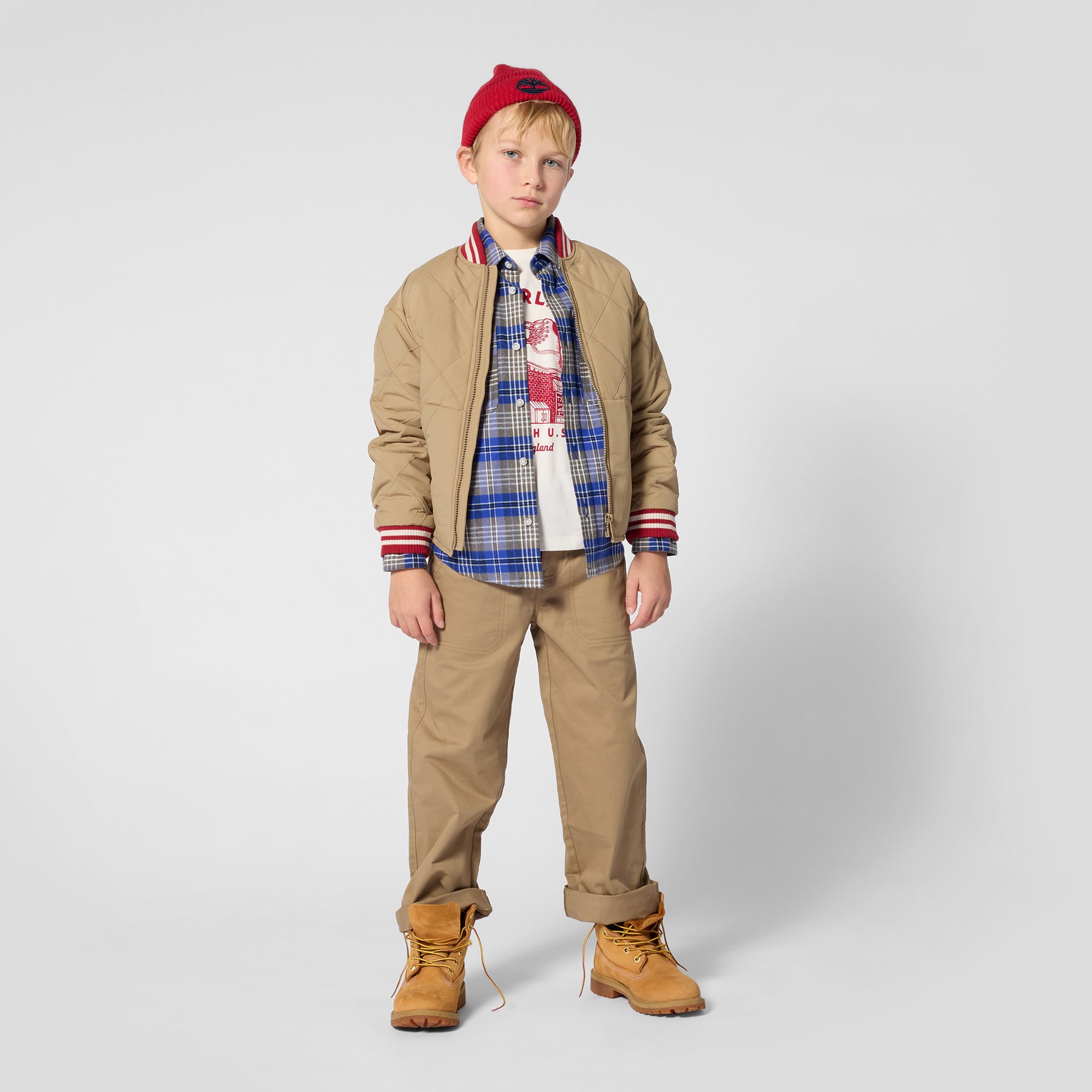 Boy wearing Timberland blue plaid shirt with tan jacket and chinos