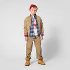 Boy wearing Timberland blue plaid shirt with tan jacket and chinos