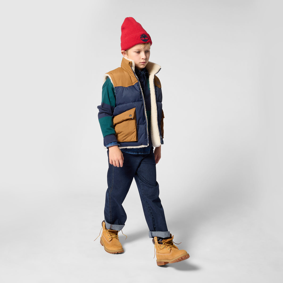 Boy wearing Timberland striped rugby shirt layered under a gilet with jeans
