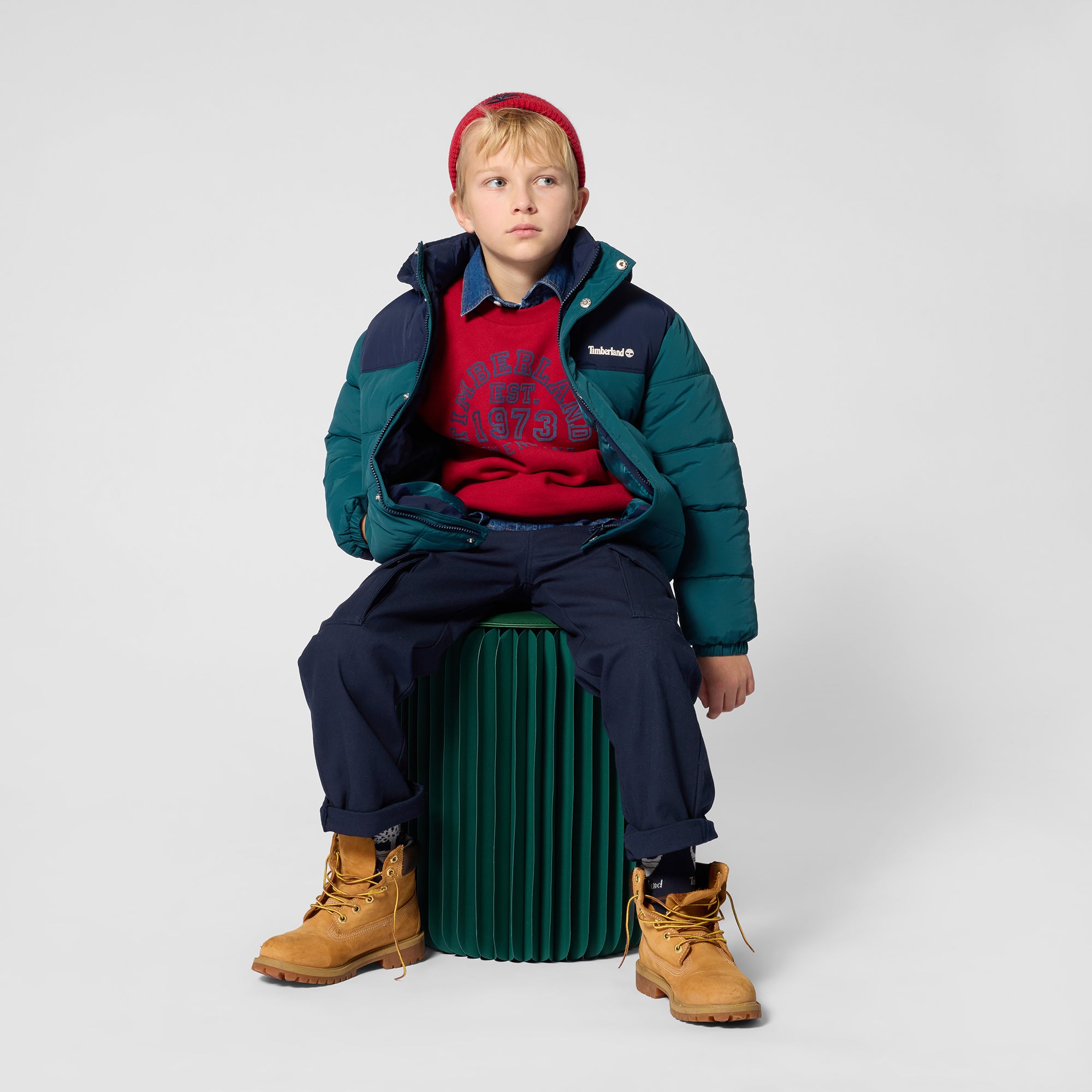 Boy wearing Timberland red graphic sweatshirt with navy trousers and winter jacket