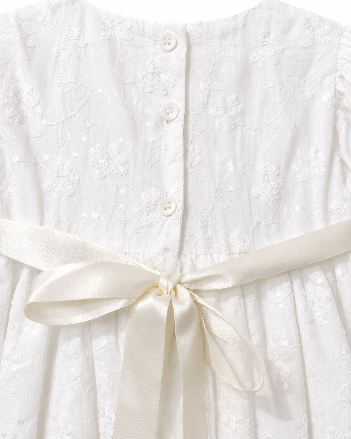 Close-up of the floral sequin embroidery, back buttons and satin bow on the Visara christening gown